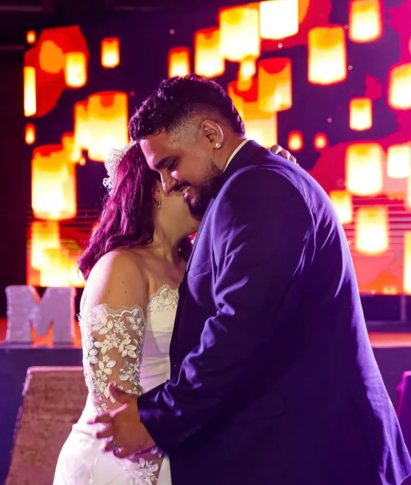 Una pareja baila frente a un fondo de luces cálidas.