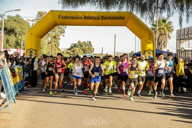 Corredores comienzan una carrera bajo un arco amarillo.